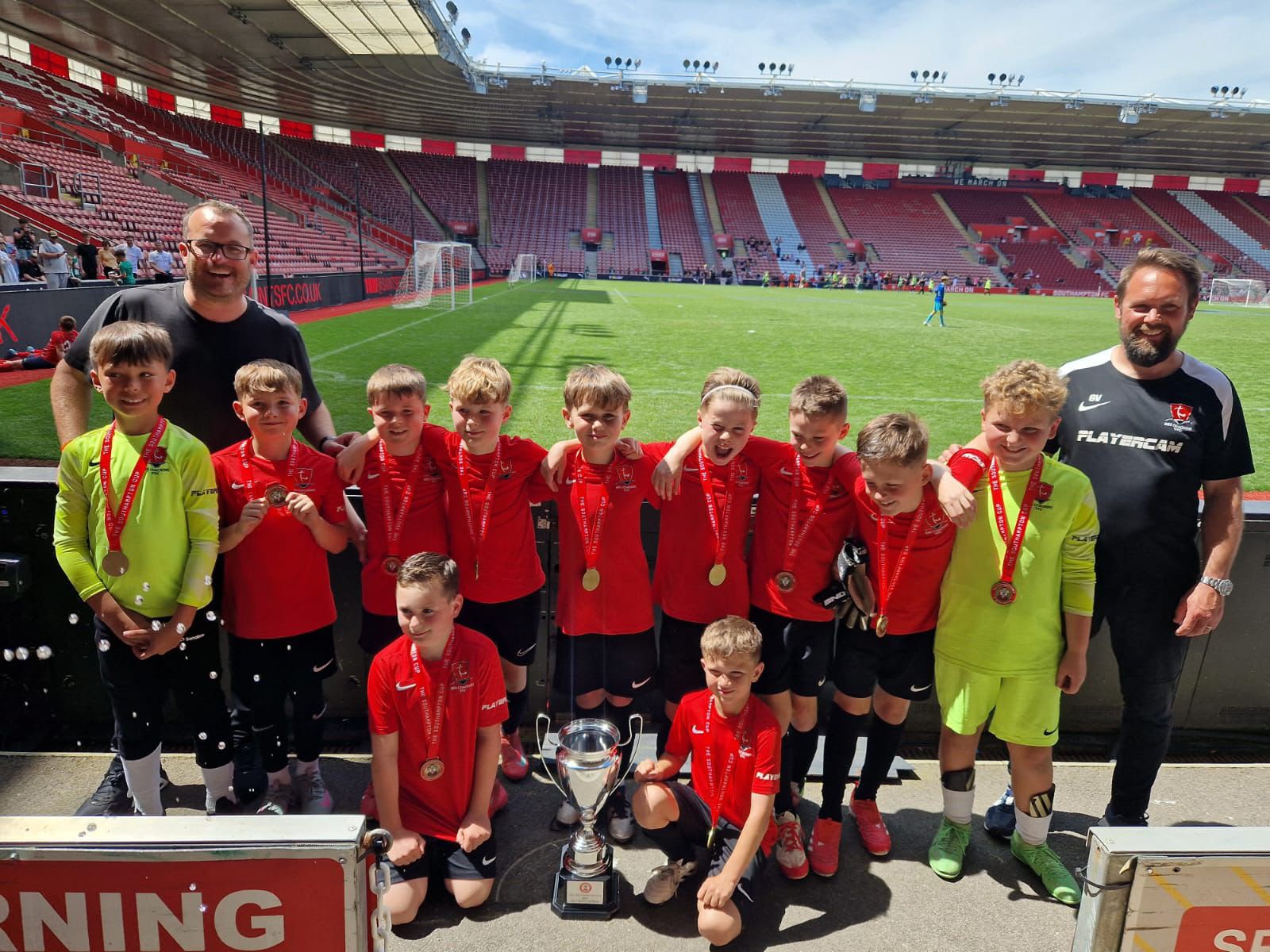 BRS youth team and coaches with their medals and trophy at a stadium